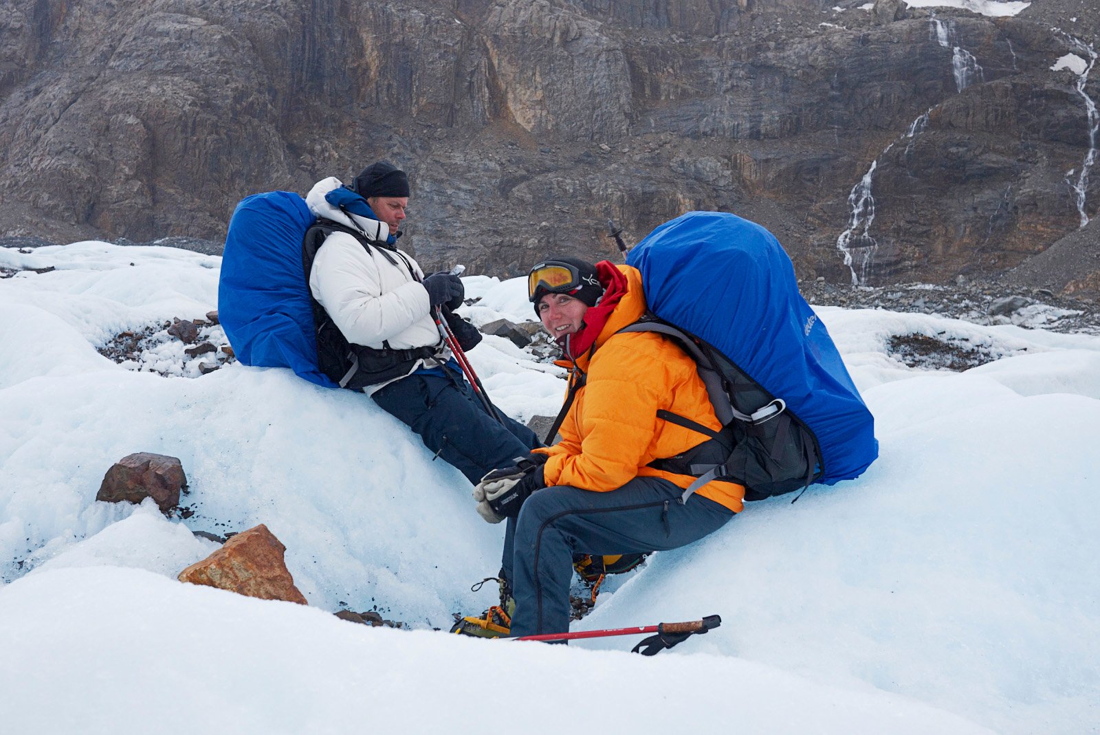 2 people sat on a glacier with very large packs